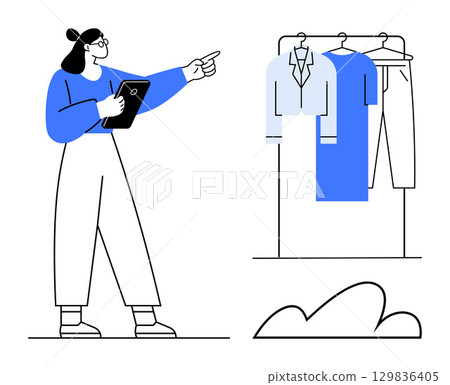 Woman holding a tablet and pointing at clothes on a rack, including a jacket, dress, and pants. Ideal for fashion advice, retail, personal shopping, style tips, online stores wardrobe planning 129836405