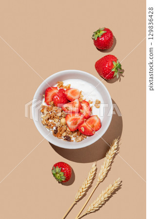 Granola or muesli with natural greek yogurt and strawberry in a bowl on a bright beige background 129836428