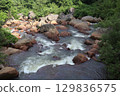 A clear stream flowing through the fresh green valley 129836575