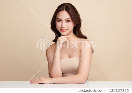 A beautiful young Asian woman with clean, fresh skin against a beige background. Skincare, facial treatment, cosmetology, beauty, and spa. An elegant portrait of an Asian woman. A beautiful young Asian woman with clean, fresh skin against a beige background. Skincare, facial treatment, cosmetology, beauty, and spa. An elegant portrait of an Asian woman. 129837255