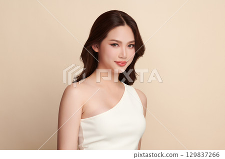 A beautiful young Asian woman with clean, fresh skin against a beige background. Skincare, facial treatment, cosmetology, beauty, and spa. An elegant portrait of an Asian woman. A beautiful young Asian woman with clean, fresh skin against a beige background. Skincare, facial treatment, cosmetology, beauty, and spa. An elegant portrait of an Asian woman. 129837266