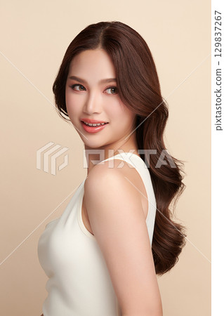 A beautiful young Asian woman with clean, fresh skin against a beige background. Skincare, facial treatment, cosmetology, beauty, and spa. An elegant portrait of an Asian woman. A beautiful young Asian woman with clean, fresh skin against a beige background. Skincare, facial treatment, cosmetology, beauty, and spa. An elegant portrait of an Asian woman. 129837267