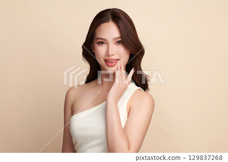 A beautiful young Asian woman with clean, fresh skin against a beige background. Skincare, facial treatment, cosmetology, beauty, and spa. An elegant portrait of an Asian woman. A beautiful young Asian woman with clean, fresh skin against a beige background. Skincare, facial treatment, cosmetology, beauty, and spa. An elegant portrait of an Asian woman. 129837268
