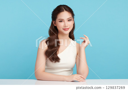 A beautiful young Asian woman with clean, fresh skin against a blue background. Skincare, facial treatment, cosmetology, beauty, and spa. An elegant portrait of an Asian woman. A beautiful young Asian woman with clean, fresh skin against a blue background. Skincare, facial treatment, cosmetology, beauty, and spa. An elegant portrait of an Asian woman. 129837269