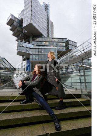 Two stylish women posing near modern architecture 129837408