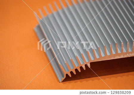 The aluminum heat sink parts on the orange background. The aluminum heat sink parts on the orange background. 129838209