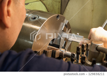 Close up scene the machine operator measuring dimension of metal shaft parts by Vernier caliper. Close up scene the machine operator measuring dimension of metal shaft parts by Vernier caliper. 129838211