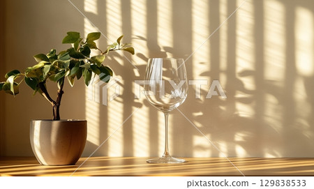 A wine glass sits on a table next to a plant 129838533