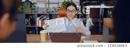 A skilled and professional woman is giving a presentation of data in a modern office environment A skilled and professional woman is giving a presentation of data in a modern office environment 129838663