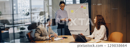 Attend a business meeting featuring an engaging presentation in a modern office setting Attend a business meeting featuring an engaging presentation in a modern office setting 129838664