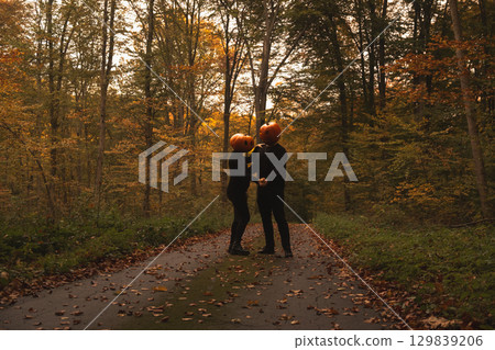 Couple in Pumpkin Heads Amidst Autumn Forest Couple in Pumpkin Heads Amidst Autumn Forest 129839206