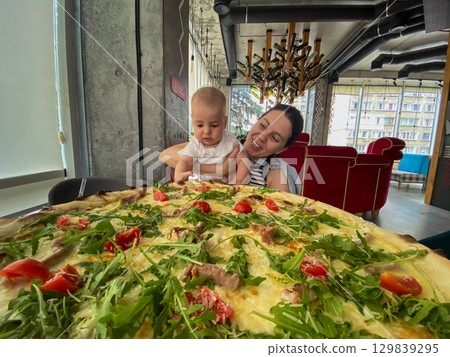 Mother and Baby Enjoying Pizza at a Restaurant 129839295