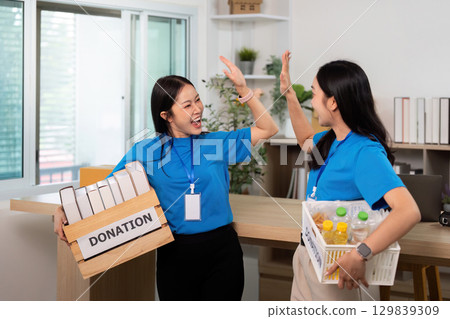 Volunteer teamwork in donation drive, celebrating contributions with joy 129839309