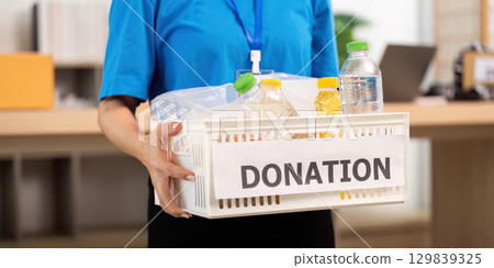 Dedicated volunteer carrying a donation basket with essential supplies 129839325