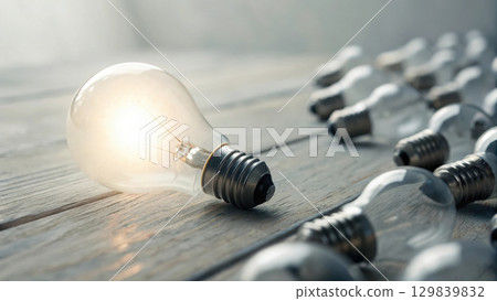 glowing light bulb stands out among dull ones, symbolizing innovation 129839832
