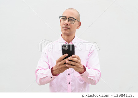 Bald man using phone texting sms message against white background 129841153