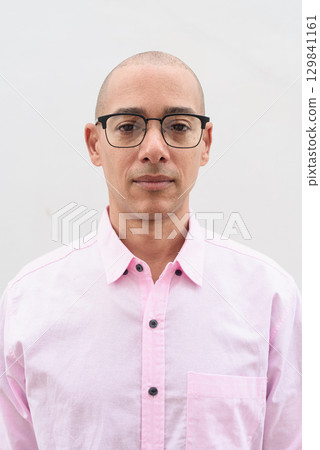 Bald Hispanic man wearing pink casual business shirt and eyeglasses against white background Bald Hispanic man wearing pink casual business shirt and eyeglasses against white background 129841161