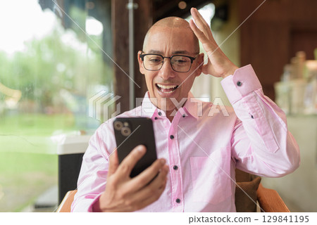 Stressed man using phone in coffee shop having headache Stressed man using phone in coffee shop having headache 129841195