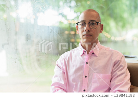 Bald Hispanic man wearing pink casual business shirt and eyeglasses in coffee shop cafe restaurant 129841198