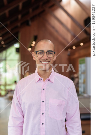 Bald Hispanic man wearing pink casual business shirt and eyeglasses in coffee shop cafe restaurant Bald Hispanic man wearing pink casual business shirt and eyeglasses in coffee shop cafe restaurant 129841227