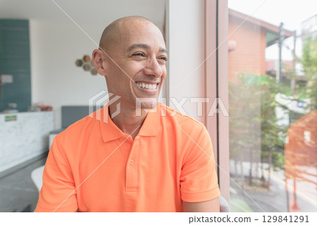 Bald Hispanic man face inside cafe restaurant wearing orange polo shirt Bald Hispanic man face inside cafe restaurant wearing orange polo shirt 129841291