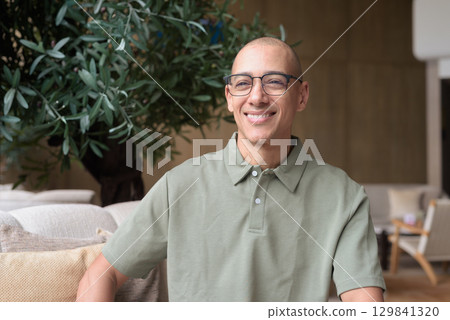 Bald Hispanic man in hotel lobby with eyeglasses, stylish confident portrait in casual setting 129841320