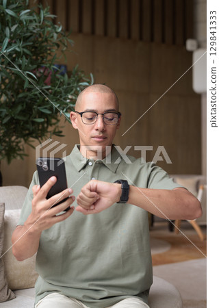 Hispanic bald man using smartphone in hotel lounge cafe, casual lifestyle and communication Hispanic bald man using smartphone in hotel lounge cafe, casual lifestyle and communication 129841333