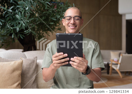 Latin adult man using tablet computer in hotel lounge or bar, travel lifestyle and technology focus Latin adult man using tablet computer in hotel lounge or bar, travel lifestyle and technology focus 129841334