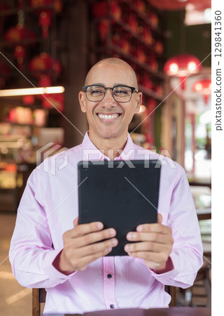 Bald Hispanic man wearing pink casual business shirt and eyeglasses in Chinese style tea house 129841360