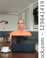Bald Hispanic man smiling and using laptop computer in coffee shop restaurant while thinking 129841419