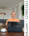 Bald Hispanic man smiling and using laptop computer in coffee shop restaurant 129841421