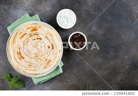 Indian flatbread paratha with raita sauce and chutney on gray background, top view. Indian food. 129841802