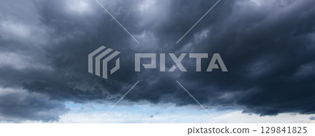 Dark stormy clouds dominate the sky as a looming windstorm signals bad weather, showcasing nature intensity and the unpredictable power of atmospheric conditions. 129841825
