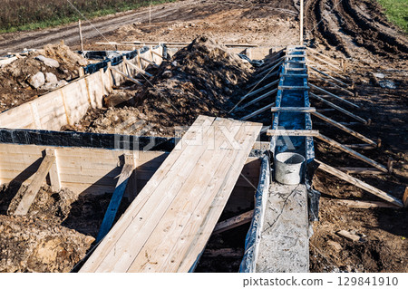Trench digging and laying foundation for strip foundation of future house building Trench digging and laying foundation for strip foundation of future house building 129841910