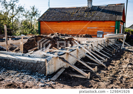 Building strip foundation for new house near old wooden house Building strip foundation for new house near old wooden house 129841926