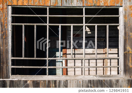 Old broken window with bars showing peeling paint on wooden wall Old broken window with bars showing peeling paint on wooden wall 129841931