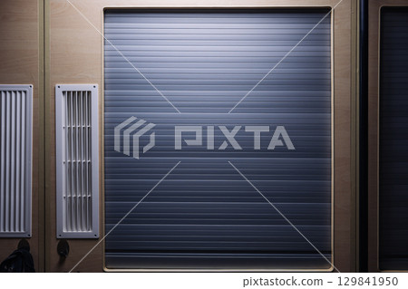 Closed rolling shutter door and ventilation grilles in a modern interior design 129841950