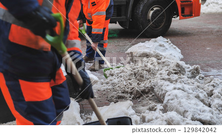 Municipal workers removing snow with shovels from city street 129842042