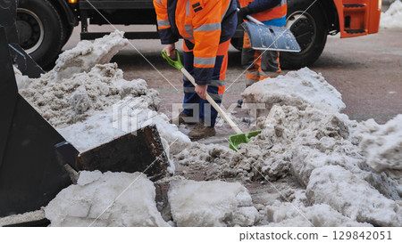 Tractor shovel loading snow and ice into truck during winter road cleaning 129842051