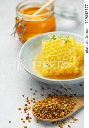 Honey, honeycomb and bee pollen creating delicious golden composition Honey, honeycomb and bee pollen creating delicious golden composition 129842177