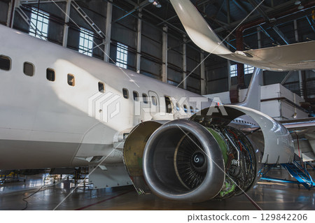 White passenger jetliner in the aircraft hangar. Airplane under maintenance. Checking mechanical systems for flight operations 129842206