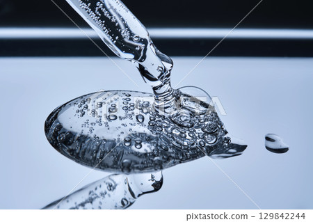 A pipette with hyaluronic serum on a blue background. 129842244