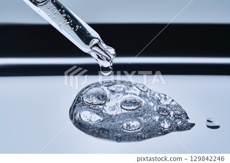 The texture of cosmetic serum in a pipette on a blue background. 129842246