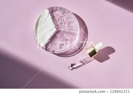 Pipettes and texture of cosmetic products in a petri dish on a purple background. Pipettes and texture of cosmetic products in a petri dish on a purple background. 129842251