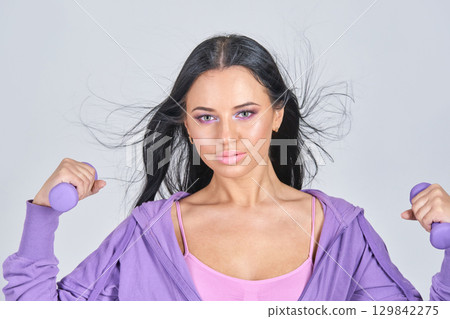 Young caucasian female with dumbbells in activewear exercising with confidence 129842275