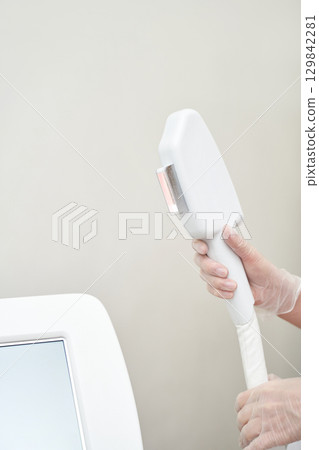 Female hands in gloves holding laser hair removal device in clinic setting Female hands in gloves holding laser hair removal device in clinic setting 129842281