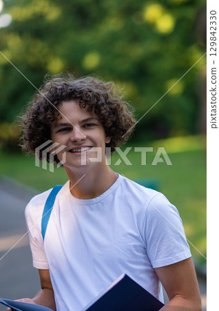 Curly-haired teen in white tshirt looking joyful and contented Curly-haired teen in white tshirt looking joyful and contented 129842330