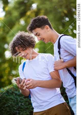 Two teens spending time together and watching something on the phone Two teens spending time together and watching something on the phone 129842338
