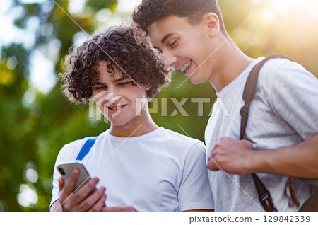 Two teens spending time together and watching something on the phone Two teens spending time together and watching something on the phone 129842339