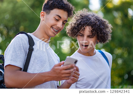 Two teens spending time together and watching something on the phone Two teens spending time together and watching something on the phone 129842341